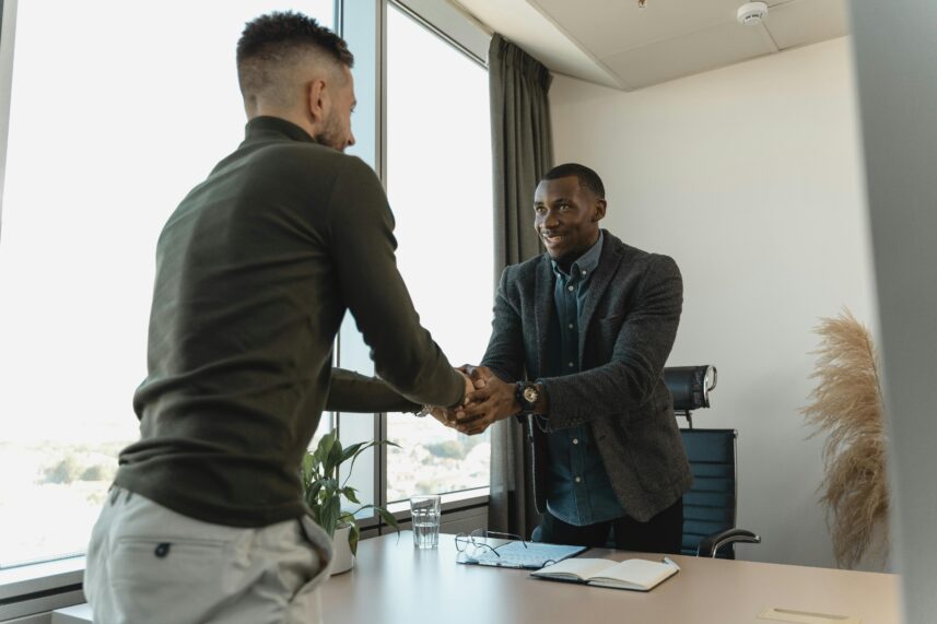 2 men shaking hands over a desk