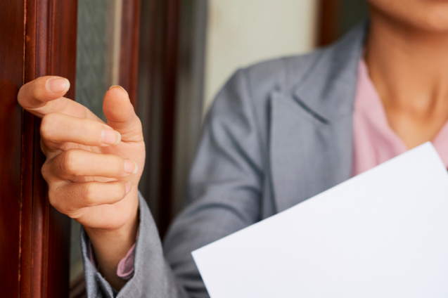 A Woman knocking on the door of an office.